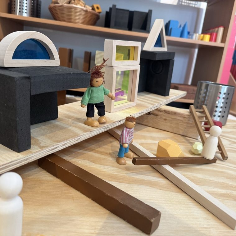 A small-world play scene of wooden figures and blocks on a table
