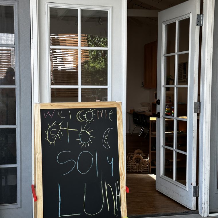 A 'Welcome to Sol y Luna' chalkboard easel at the school entrance