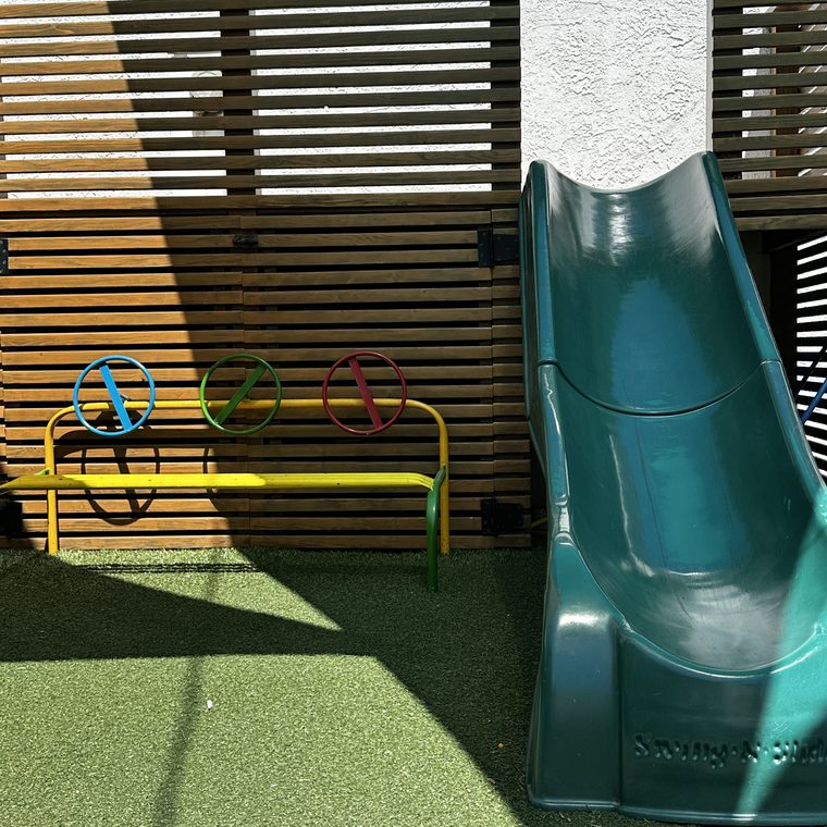 A green tube slide and play structure in the outdoor play space