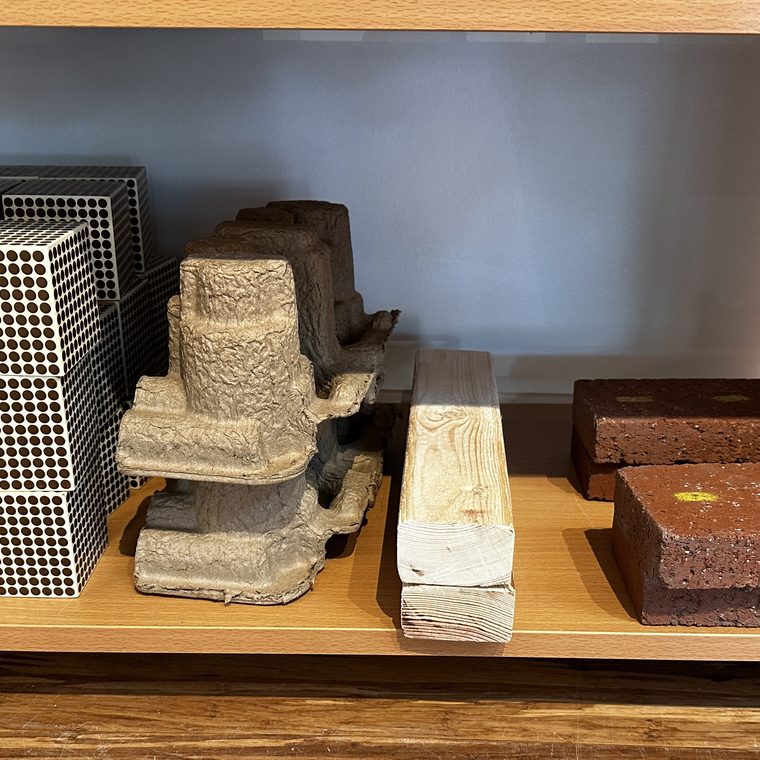 A shelf of bead cubes, natural loose parts, a wood beam, and bricks