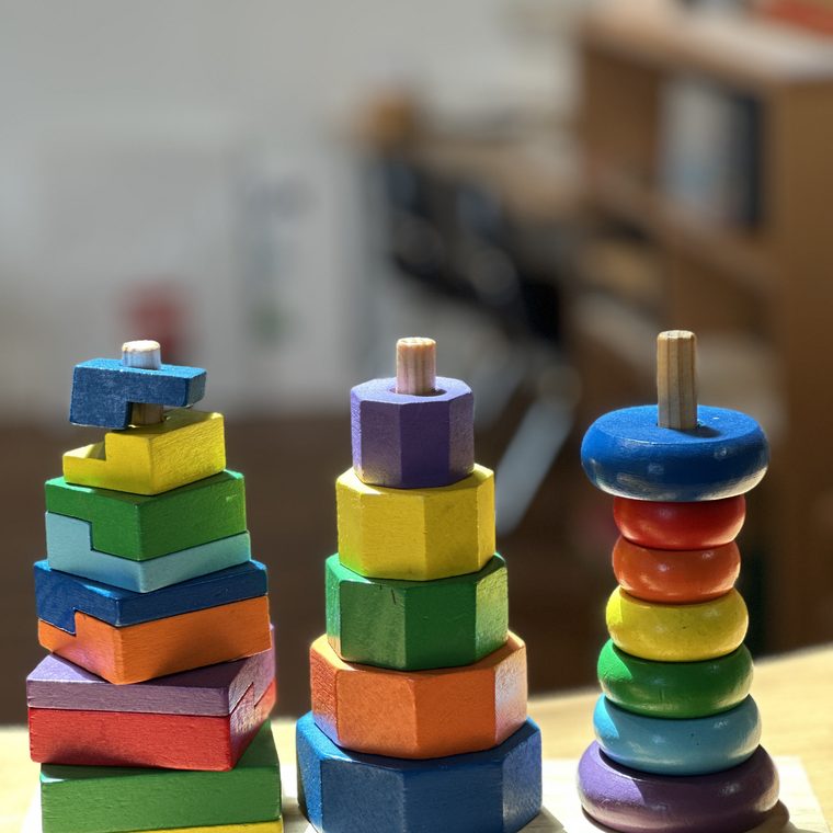 Wooden rainbow stacking toys on a sunlit table