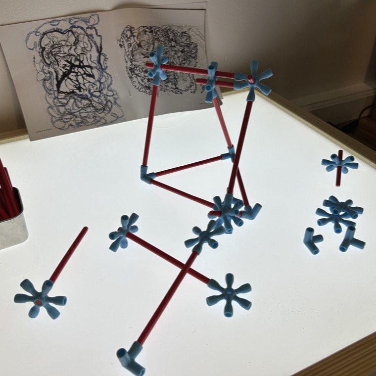 Red rods and blue connectors arranged on a glowing light table