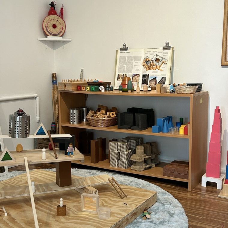 Montessori shelves with the pink tower and materials on a round rug