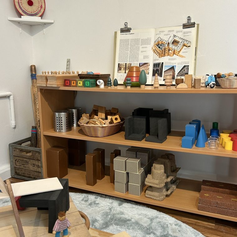 Shelves of wooden blocks and materials beside an open book