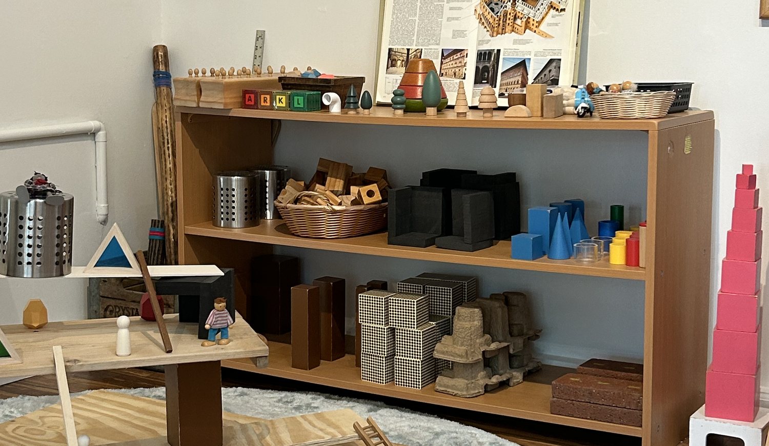 Classroom shelves filled with Montessori materials and natural wooden blocks